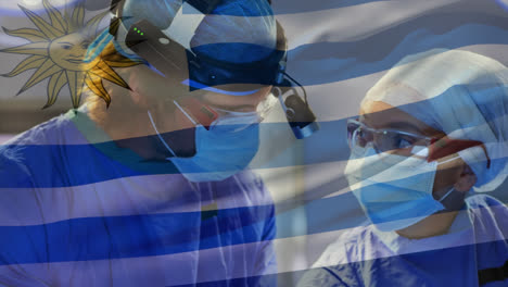 Animation-of-uruguay-flag-against-diverse-male-and-female-surgeons-performing-operation-at-hospital