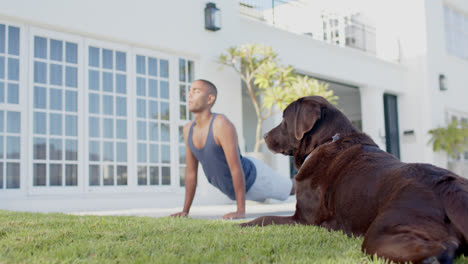 Fokussierter-Biracial-Mann,-Der-Yoga-Mit-Hund-Im-Sonnigen-Garten-Praktiziert,-Zeitlupe
