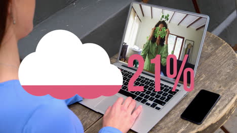Animation-of-cloud-upload-icon-against-rear-view-of-woman-having-a-video-call-on-laptop-at-a-cafe