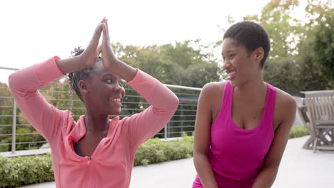 Glückliche-Afroamerikanische-Tochter-Und-Mutter-Praktizieren-Yoga-Und-Lächeln-Im-Garten,-Zeitlupe