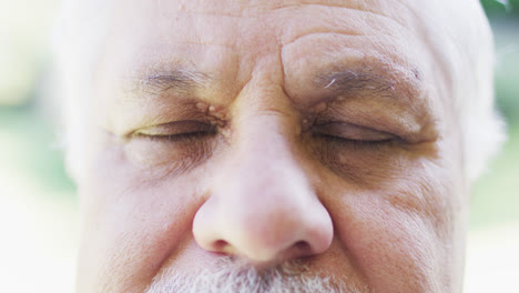 Portrait-close-up-of-senior-biracial-man-outdoors-opening-and-closing-eyes