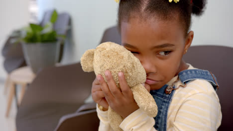 Sad-african-american-girl-sitting-in-hospital-waiting-room-and-holding-mascot,-slow-motion