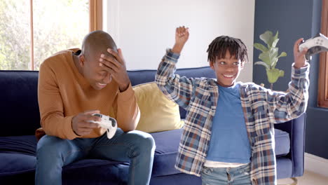 Glücklicher-Afroamerikanischer-Vater-Und-Sohn-Spielen-Videospiele-Zu-Hause,-Zeitlupe