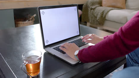 Hands-of-biracial-woman-using-laptop-with-copy-space-on-screen-at-home,-slow-motion