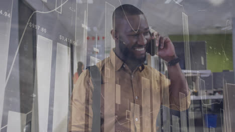 Animation-of-data-processing-against-happy-african-american-man-talking-on-smartphone-at-office