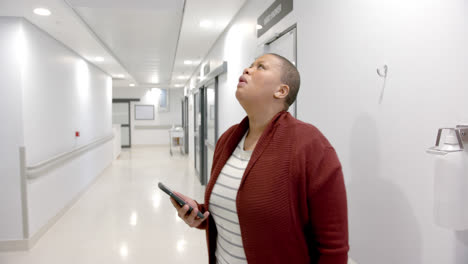 Stressed-african-american-woman-using-smartphone-in-hospital-corridor,-slow-motion