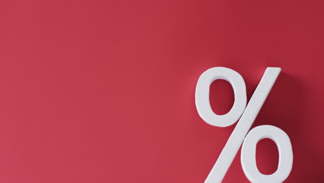Video-of-white-percent-sign-with-copy-space-against-red-background