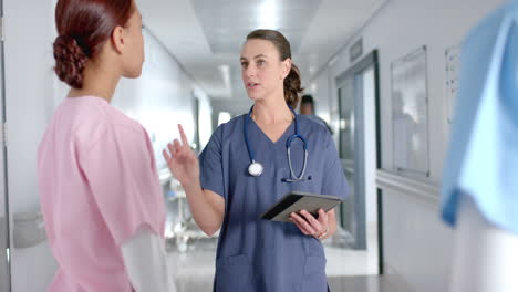 Caucasian-nurse-talking-with-a-nurse-in-a-hospital-corridor