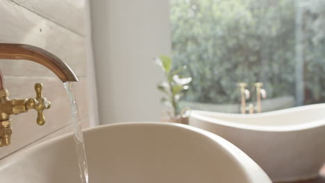 Close-up-of-washbasin-with-running-water-in-bathroom,-slow-motion