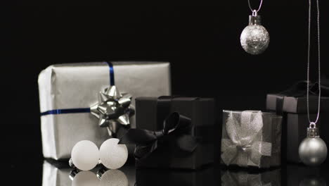 Video-of-silver-baubles-christmas-decorations-and-gifts-with-copy-space-on-black-background