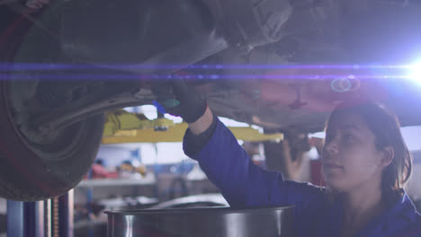 Animation-of-glowing-purple-light-over-biracial-female-car-mechanic-fixing-car