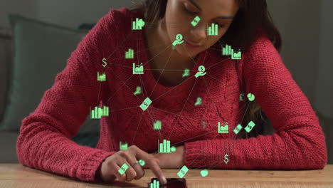 Animation-of-network-of-green-business-icons-over-woman-using-laptop-writing-in-notebook