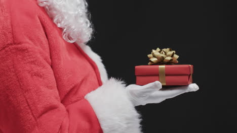 Video-Vom-Weihnachtsmann,-Der-Ein-Weihnachtsgeschenk-Hält,-Mit-Kopierplatz-Auf-Schwarzem-Hintergrund