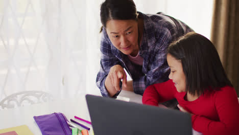 Video-of-happy-asian-mother-and-daughter-doing-homework-together