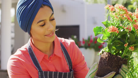 Video-Einer-Glücklichen-Frau-Mit-Gemischter-Abstammung-Im-Hijab,-Die-Im-Garten-Blumen-Pflanzt