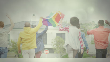 Diverse-group-of-people-holding-rainbow-flag-while-walking-towards-building