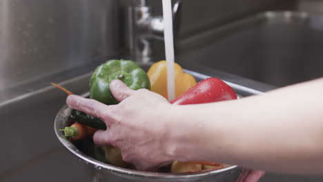 Caucasian-male-chef-washing-vegetables-in-sink-in-kitchen,-slow-motion