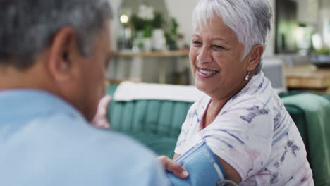 Senior-diverse-couple-talking-and-measuring-blood-pressure