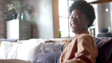 Porträt-Eines-Glücklichen-Afroamerikanischen-Mannes-Mit-Afro,-Der-Zu-Hause-Auf-Dem-Sofa-Sitzt,-Zeitlupe