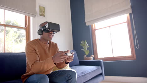 African-american-man-playing-video-game-using-vr-headset-at-home,-slow-motion