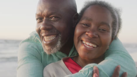 Portrait-of-happy-senior-african-american-couple-embracing-at-beach,-in-slow-motion