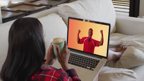 Biracial-woman-watching-laptop-with-african-american-male-rugby-player-celebrating-on-screen