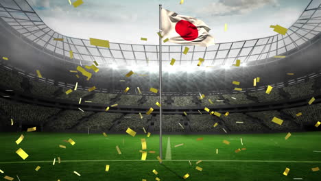 Animation-Von-Goldenem-Konfetti,-Das-über-Die-Wehende-Japanische-Flagge-Vor-Einem-Sportstadion-Fällt