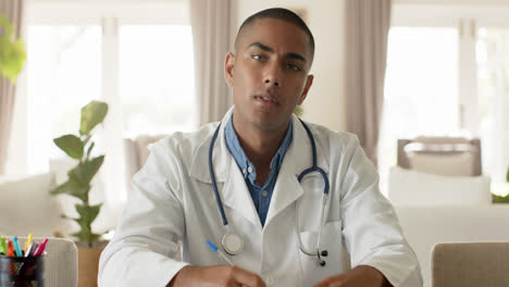 Biracial-male-doctor-making-video-call-in-bright-room,-slow-motion