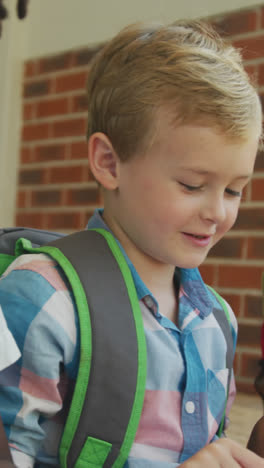 Video-of-happy-diverse-boys-holding-books-and-talking-in-front-of-school