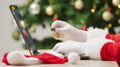 Santa-claus-using-laptop-over-christmas-tree-and-lights