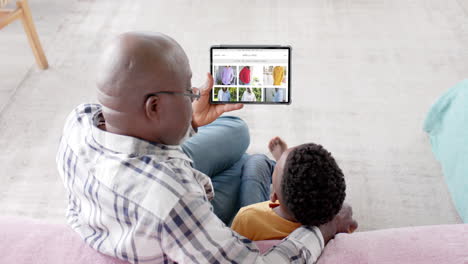 African-american-grandfather-and-grandson-using-tablet,-shopping-online-for-clothes,-slow-motion