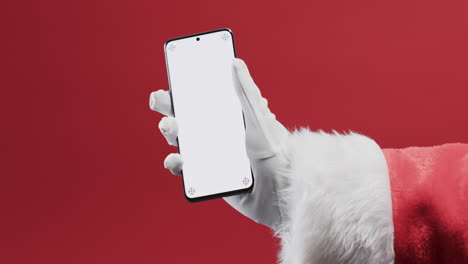 Video-of-santa-claus-holding-smartphone-with-copy-space-on-red-background