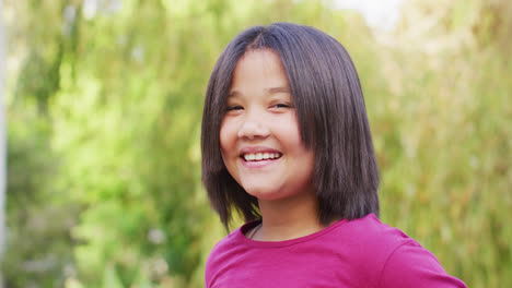 Video-Eines-Porträts-Eines-Glücklichen-Asiatischen-Mädchens,-Das-Im-Garten-Posiert