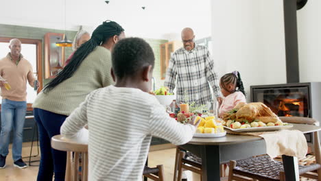 Happy-african-american-multi-generation-family-serving-food-at-thanksgiving-dinner,-slow-motion