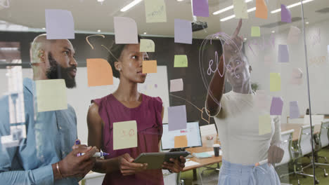 African-american-colleagues-brainstorming,-making-notes-on-glass-wall-in-office-in-slow-motion
