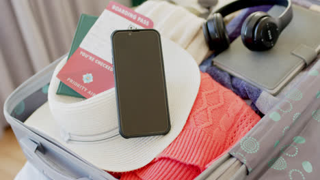 Close-up-of-a-plane-ticket,-passport,-smartphone,-tablet-and-headphones-in-suitcase