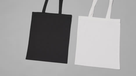 Close-up-of-white-and-black-bags-on-grey-background,-with-copy-space,-slow-motion