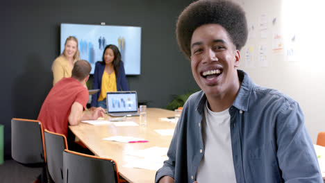 Portrait-of-happy-biracial-casual-businessman-with-colleagues-in-meeting-room,-slow-motion