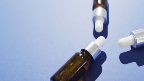 Close-up-of-dropper-serum-bottles-on-blue-background-with-copy-space