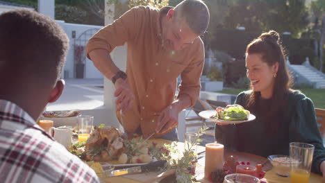 Happy-diverse-male-and-female-friends-serving-thanksgiving-celebration-meal-in-sunny-garden
