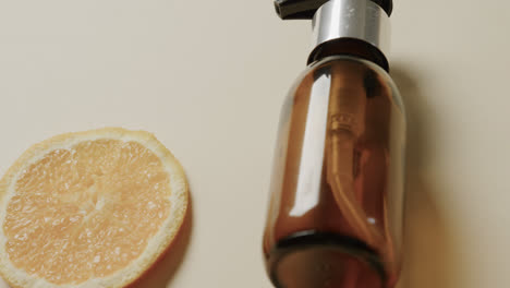 Close-up-of-glass-bottle-with-pump,-lemon-slice-and-copy-space-on-beige-background