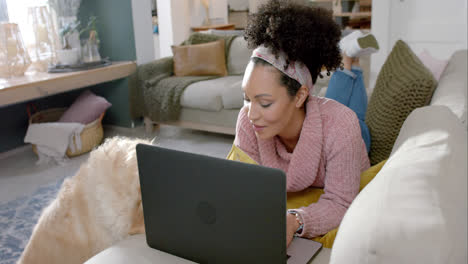 Happy-biracial-woman-with-golden-retriever-dog-using-laptop-and-credit-card-at-home,-slow-motion