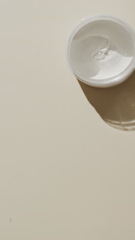 Vertical-video-of-close-up-of-cream-tub-on-white-background