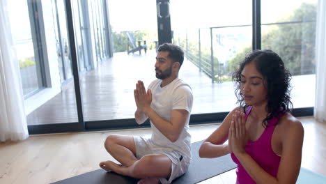 Biracial-couple-doing-yoga-and-meditating-at-home,-in-slow-motion