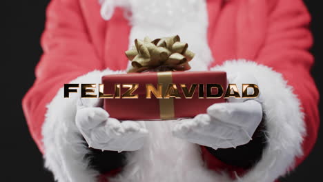 Feliz-navidad-text-in-gold-over-midsection-of-father-christmas-holding-gift