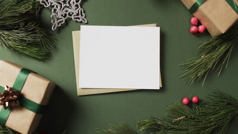 Video-of-christmas-decorations-and-white-card-with-copy-space-on-green-background