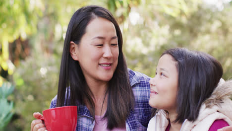Video-Einer-Glücklichen-Asiatischen-Mutter-Und-Tochter,-Die-Sich-Im-Garten-Umarmen-Und-Unterhalten