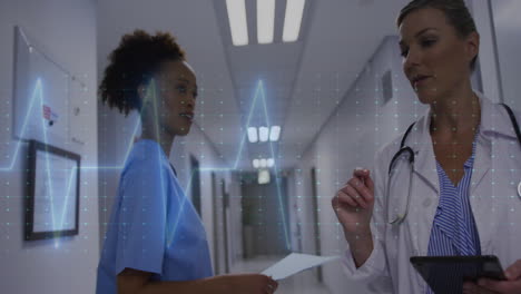 Animation-of-heart-rate-monitor-over-diverse-female-doctor-and-health-workers-discussing-at-hospital