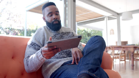 Hombre-Afroamericano-Usando-Tableta-Y-Tarjeta-De-Crédito-En-Una-Sala-De-Estar-Soleada,-Cámara-Lenta