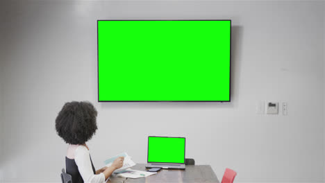African-american-businesswoman-on-video-call-with-tv-green-screen